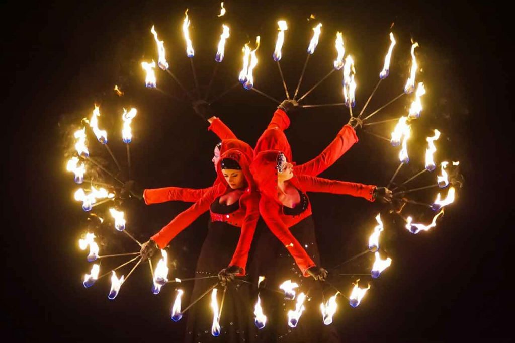 Drei Tänzerinnen mit Feuerfackeln Rücken an Rücken bei einer Feuershow der FIREDANCER